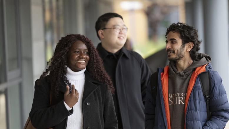 Three international students walk towards Rik Medlik building