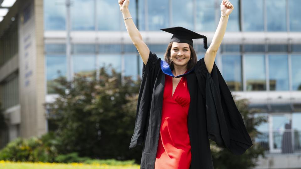 A graduate celebrating with her hands in the air