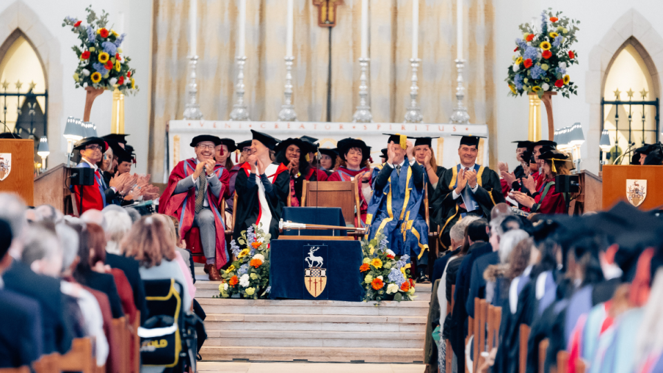 A photo from a graduation ceremony, showing the procession guests sitting in the Cathedral