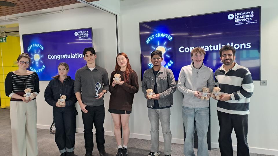 The finalists standing in front of two screens saying Congratulations
