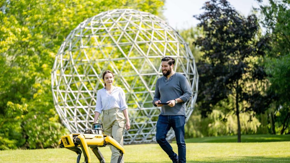 Postgraduate computer science students on campus operating Boston Dynamics robot dog