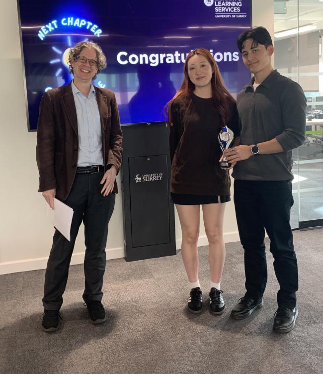 Paul, Yuki and Eden in front of a screen saying Congratulations